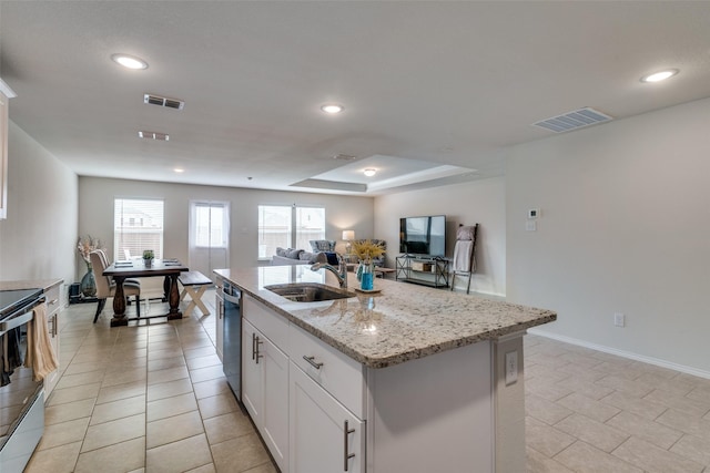 kitchen featuring sink, light stone counters, a center island with sink, white cabinets, and appliances with stainless steel finishes