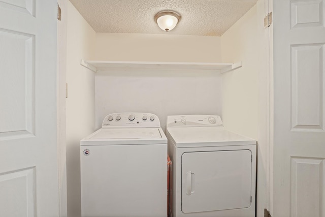 laundry room with washing machine and clothes dryer and a textured ceiling