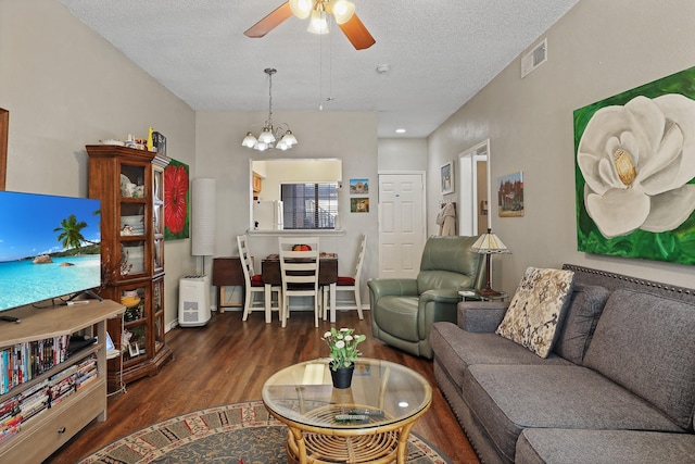 living room with dark hardwood / wood-style flooring, ceiling fan with notable chandelier, and a textured ceiling