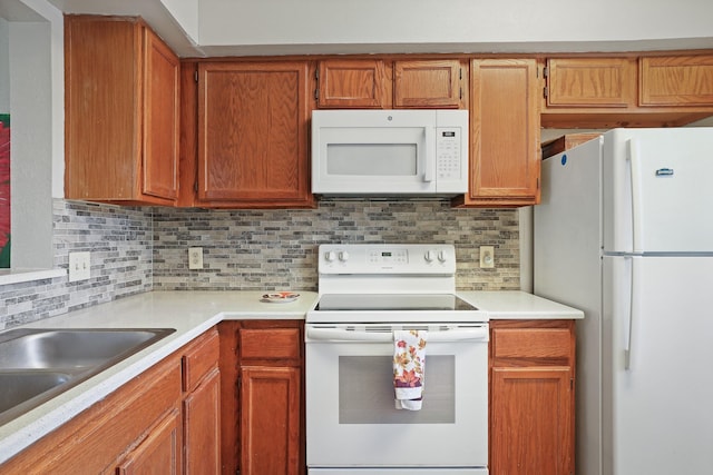 kitchen featuring sink, white appliances, and backsplash