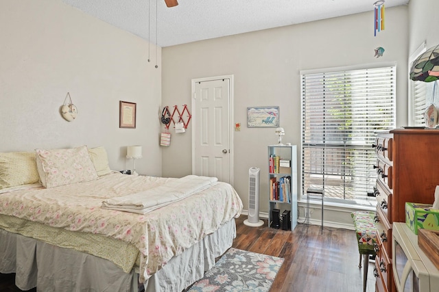 bedroom with a textured ceiling, ceiling fan, and dark hardwood / wood-style floors