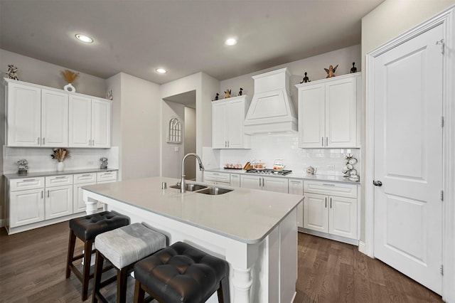 kitchen featuring dark hardwood / wood-style flooring, premium range hood, white cabinetry, and sink