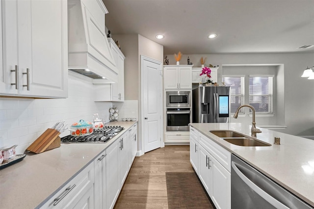 kitchen with appliances with stainless steel finishes, dark hardwood / wood-style flooring, custom range hood, sink, and white cabinetry