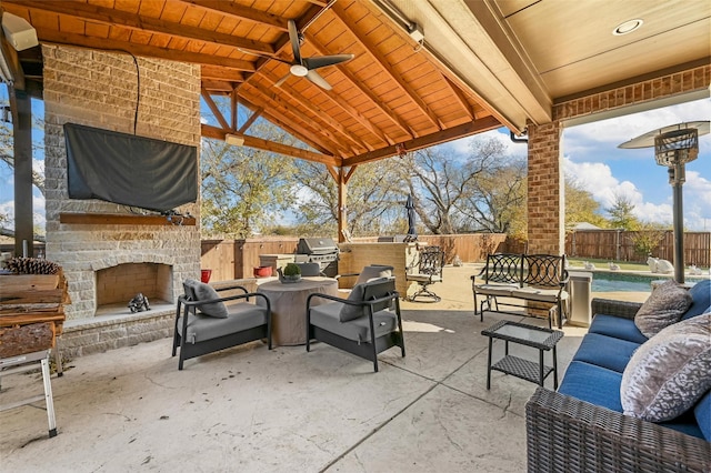 view of patio featuring a grill, ceiling fan, area for grilling, and an outdoor stone fireplace