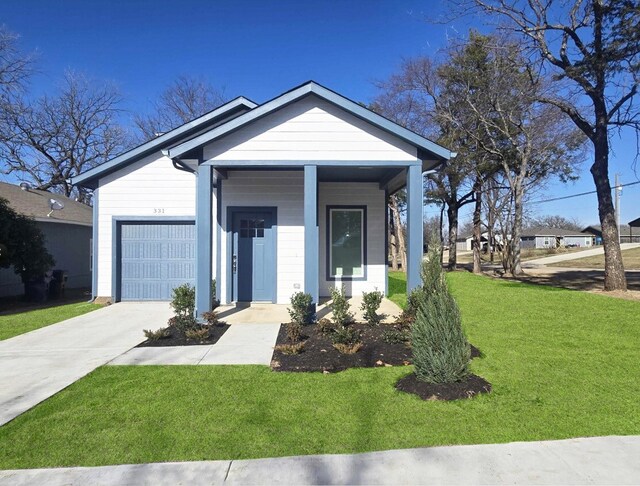 view of front of home featuring covered porch, a garage, and a front lawn