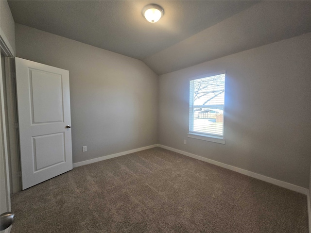 carpeted empty room featuring lofted ceiling