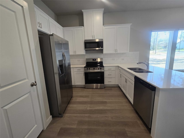 kitchen with sink, stainless steel appliances, backsplash, kitchen peninsula, and white cabinets