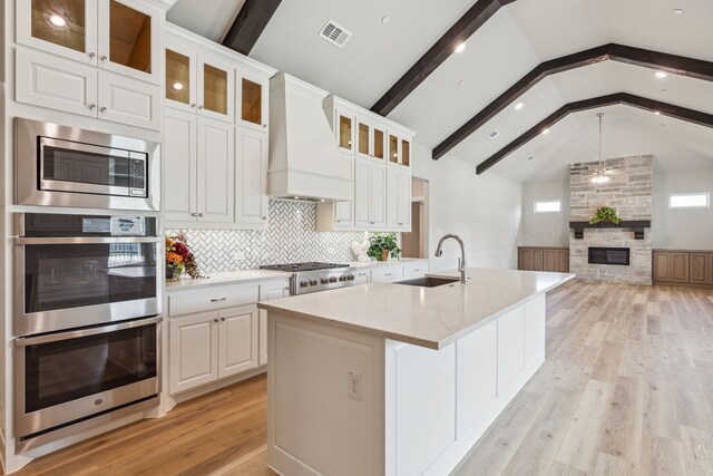 kitchen with white cabinetry, sink, light hardwood / wood-style flooring, lofted ceiling with beams, and custom exhaust hood