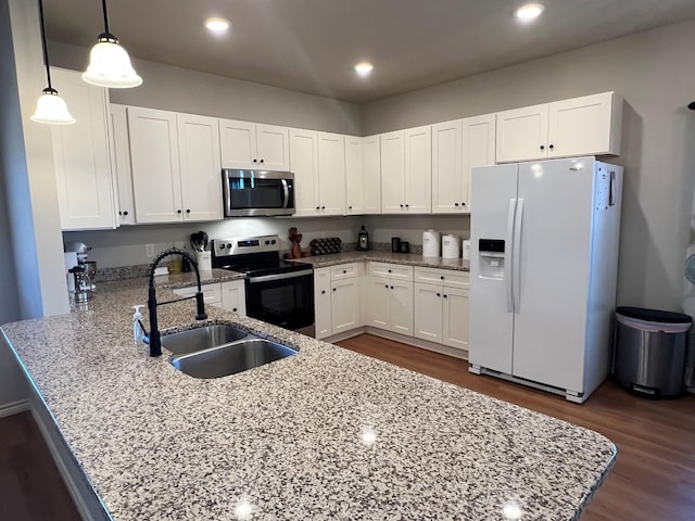 kitchen with white cabinets, decorative light fixtures, a peninsula, stainless steel appliances, and a sink