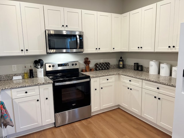 kitchen with appliances with stainless steel finishes, sink, decorative light fixtures, white cabinets, and kitchen peninsula