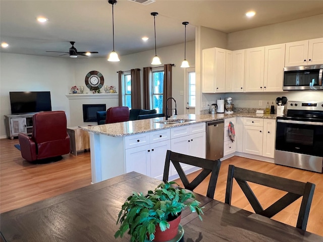 kitchen with open floor plan, appliances with stainless steel finishes, a sink, and white cabinets