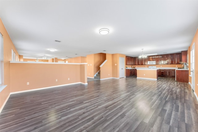 unfurnished living room with dark hardwood / wood-style flooring and a chandelier