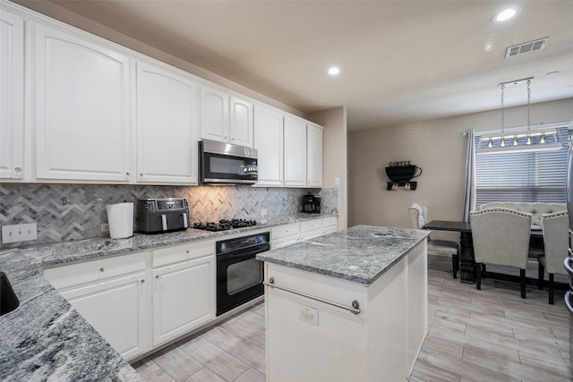 kitchen featuring pendant lighting, backsplash, oven, light stone counters, and white cabinetry