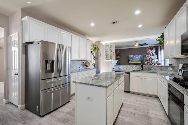 kitchen with ceiling fan, appliances with stainless steel finishes, tasteful backsplash, a kitchen island, and white cabinetry