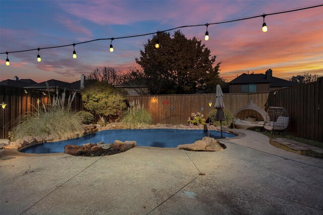 pool at dusk with a patio area