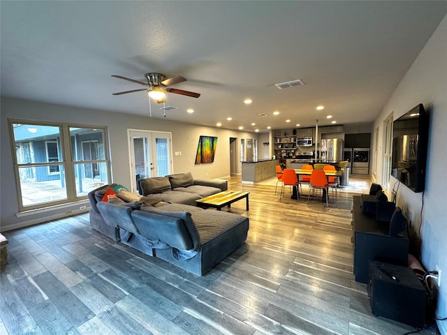 living room featuring wood-type flooring, french doors, and ceiling fan