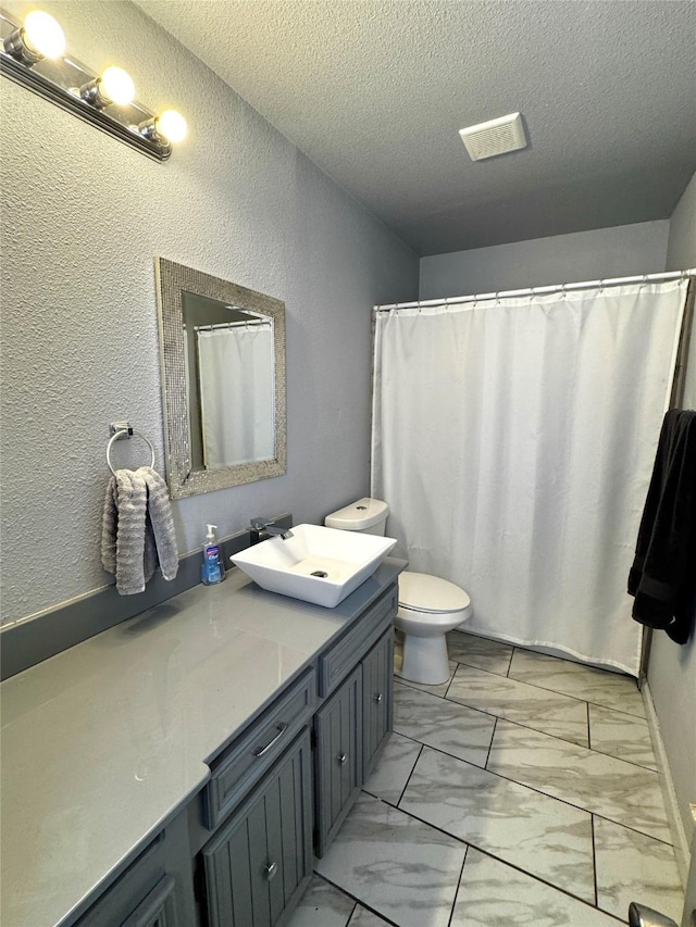 bathroom featuring vanity, a textured ceiling, and toilet