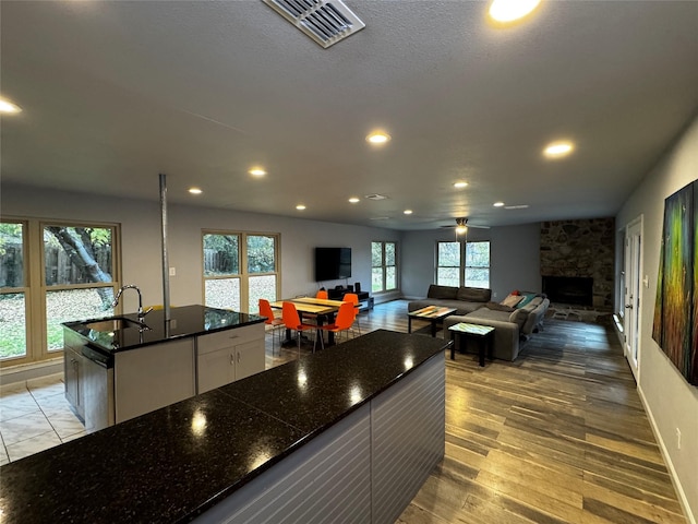 kitchen featuring white cabinets, light hardwood / wood-style floors, a center island with sink, and a wealth of natural light