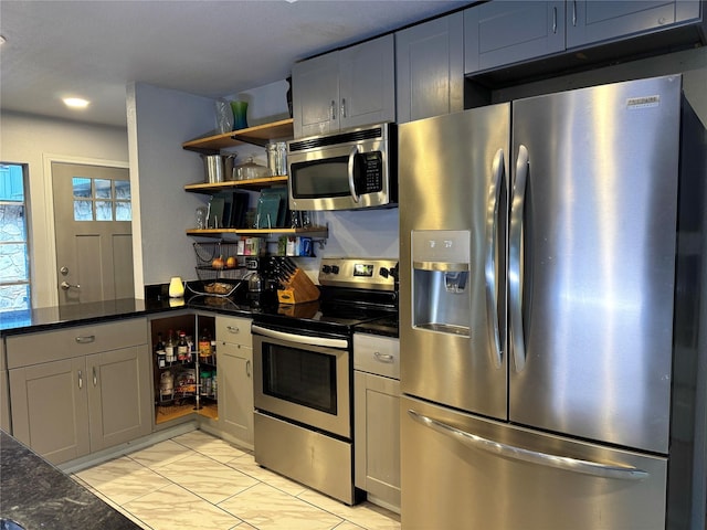 kitchen featuring dark stone countertops, gray cabinets, and appliances with stainless steel finishes