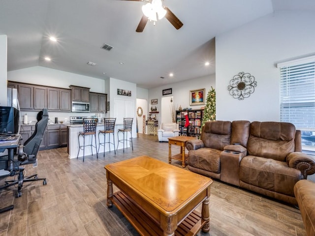 living room with ceiling fan, lofted ceiling, and light hardwood / wood-style flooring