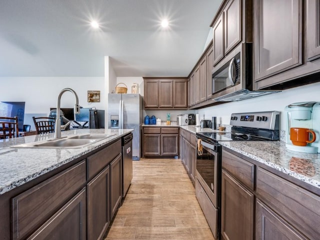 kitchen featuring sink, light hardwood / wood-style flooring, dark brown cabinets, light stone counters, and stainless steel appliances