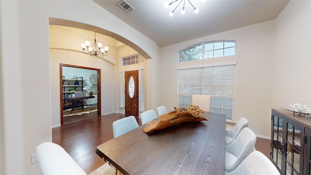 dining space with a chandelier, lofted ceiling, and dark wood-type flooring