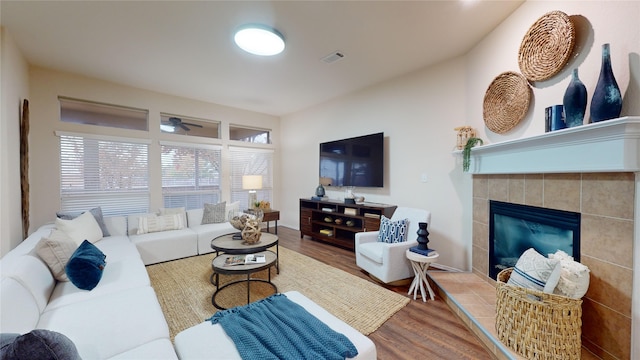 living room featuring hardwood / wood-style flooring, ceiling fan, and a fireplace