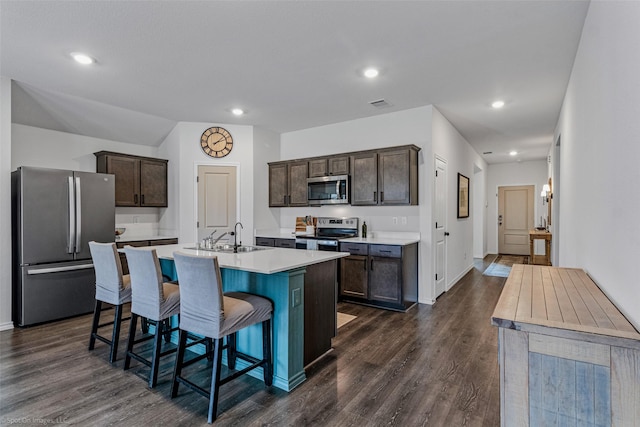 kitchen with dark brown cabinetry, a kitchen bar, sink, a center island with sink, and stainless steel appliances