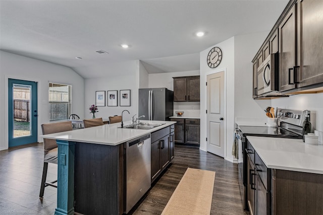 kitchen featuring dark wood-type flooring, sink, dark brown cabinets, stainless steel appliances, and a kitchen island with sink