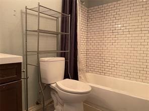 full bathroom with shower / bathtub combination with curtain, vanity, and toilet