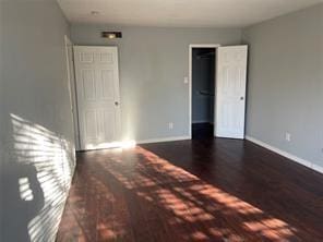 unfurnished bedroom with dark wood-type flooring and a closet