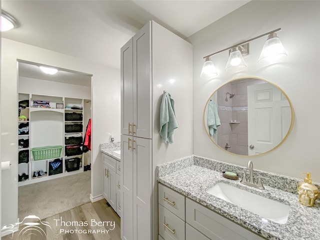 bathroom with hardwood / wood-style flooring, vanity, and a shower