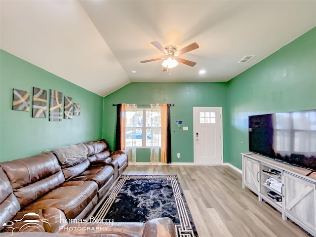 living room with ceiling fan, vaulted ceiling, and light wood-type flooring