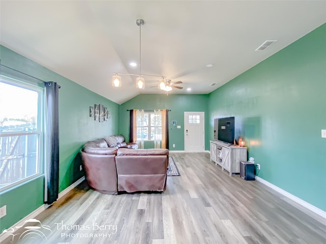 living room with ceiling fan, plenty of natural light, vaulted ceiling, and light wood-type flooring