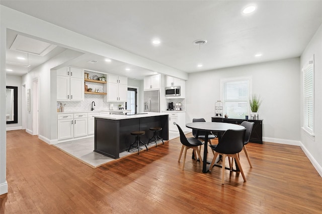 kitchen featuring white cabinets, a kitchen island, light hardwood / wood-style floors, and appliances with stainless steel finishes