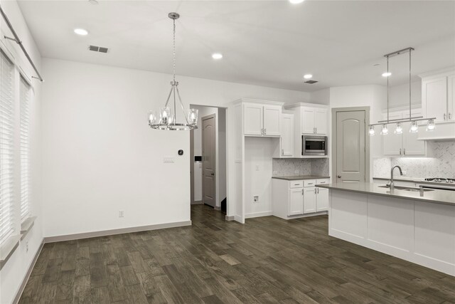 kitchen with dark wood-type flooring, sink, decorative light fixtures, white cabinetry, and stainless steel microwave