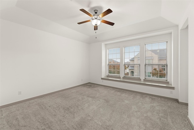 carpeted spare room with a tray ceiling and ceiling fan