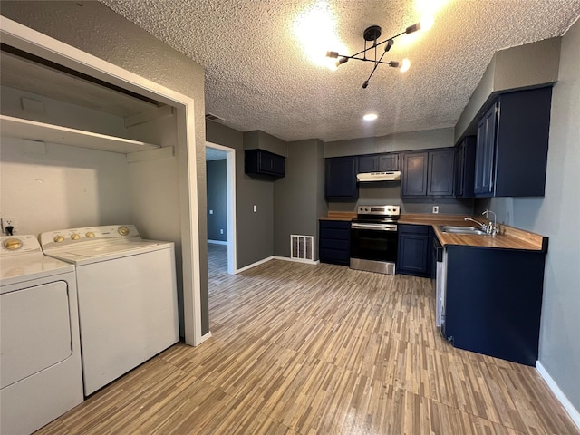 interior space with appliances with stainless steel finishes, blue cabinets, sink, washer and dryer, and butcher block counters