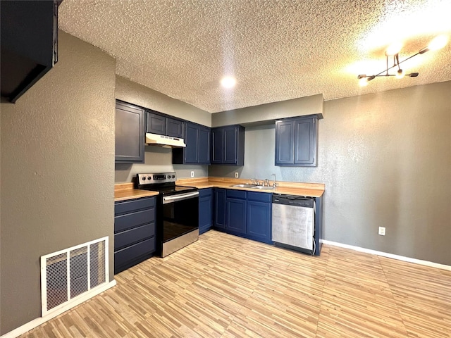 kitchen featuring appliances with stainless steel finishes, a textured ceiling, butcher block countertops, and sink