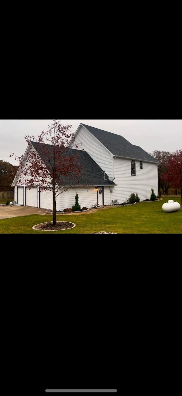 view of side of property featuring a lawn and a garage