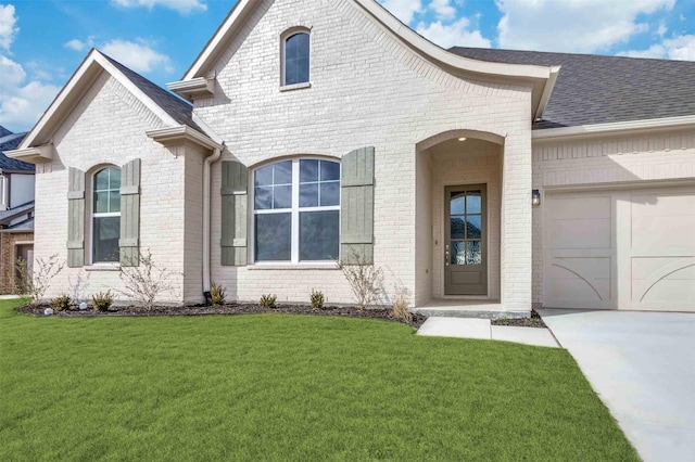 view of front of house with concrete driveway, brick siding, an attached garage, and a front lawn