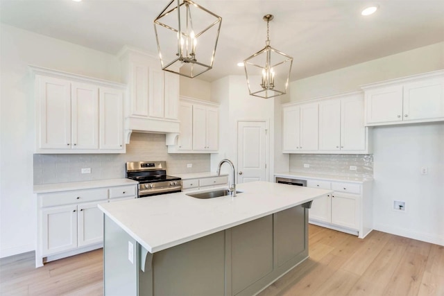 kitchen with light countertops, stainless steel range with electric cooktop, white cabinetry, pendant lighting, and a sink