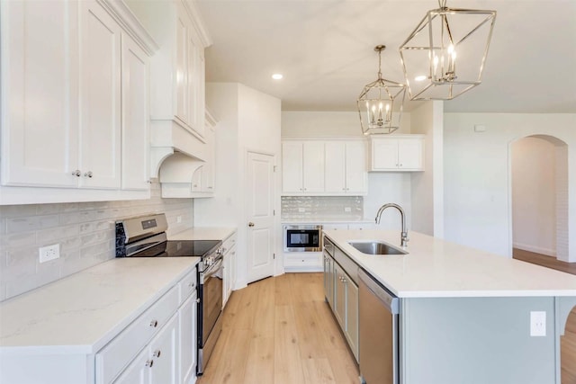 kitchen featuring a center island with sink, appliances with stainless steel finishes, white cabinets, and a sink