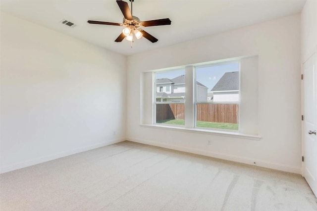 empty room featuring baseboards, visible vents, ceiling fan, and light colored carpet