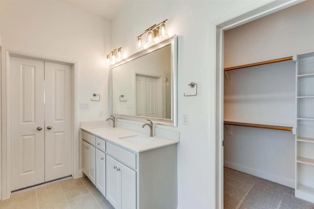 bathroom with tile patterned floors, a walk in closet, a sink, and double vanity