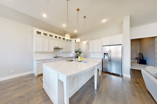 kitchen featuring decorative backsplash, stainless steel fridge, white cabinets, and a kitchen island with sink