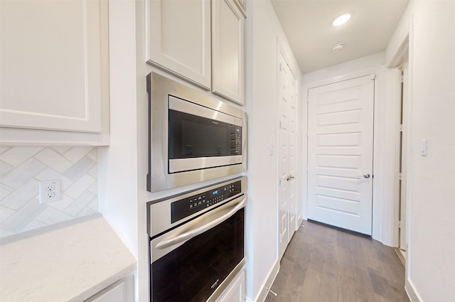 kitchen with decorative backsplash, stainless steel appliances, white cabinets, and hardwood / wood-style flooring