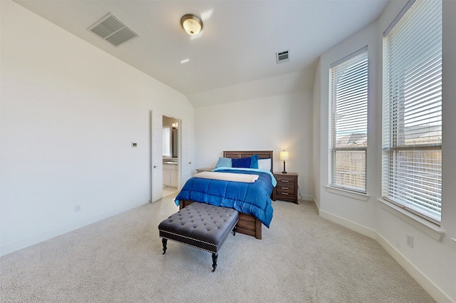 bedroom with connected bathroom, light carpet, and lofted ceiling