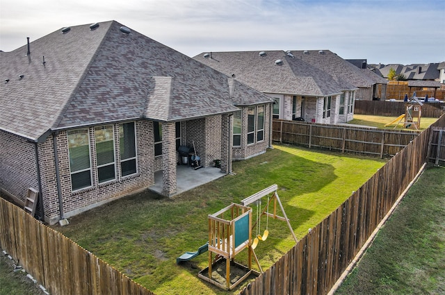 back of property with a playground, a patio area, and a yard