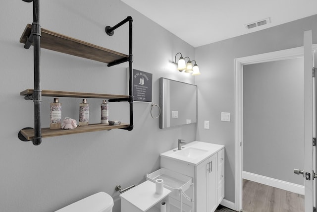 bathroom featuring toilet, vanity, and hardwood / wood-style flooring